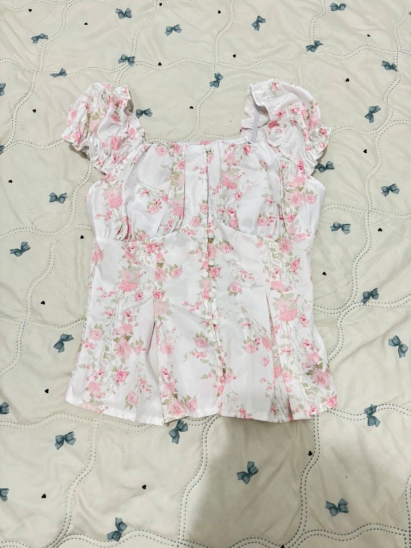 Floral Print Puff Sleeve Crop Top (Category: Blouses) located in Manila. Submitted by etani (Listing ID 1469969437, Image 1). Description: - Color & Print: White with all-over pink floral print - Design: Square neckline, ruched puff sleeves, and button-down front with small white buttons - Material: Subtle sheen finish - Fit: True to size - Styling: Pairs well with denim skirts or high-waisted jeans - Occasion: Great for casual days out or dates 