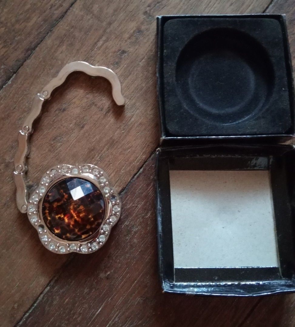 Foldable Flower Handbag Purse Hook Holder Rhinestone Tortoiseshell (Category: Purses & Pouches) located in Makati City. Submitted by YSL80022 (Listing ID 1470026844, Image 3). Description: - Elegant tortoiseshell faceted stone surrounded by sparkling rhinestones - Beautiful flower-shaped top design with silver-toned hardware - Practical fold-out hook keeps your purse clean and safely off restaurant and cafe floors - Includes original black box wi