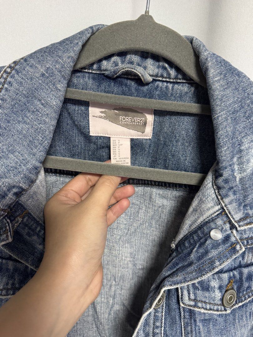 Forever 21 Cropped Denim Jacket (Category: Coats, Jackets and Outerwear) located in Calamba. Submitted by cheriiv (Listing ID 1469951111, Image 3). Description: - Brand: Forever 21 Contemporary - Size: Small - Wash: Medium wash denim - Fit: Cropped cut with classic collar and button cuffs - Details: Button-front closure, two chest pockets, and stylish distressing near the hem and shoulders.