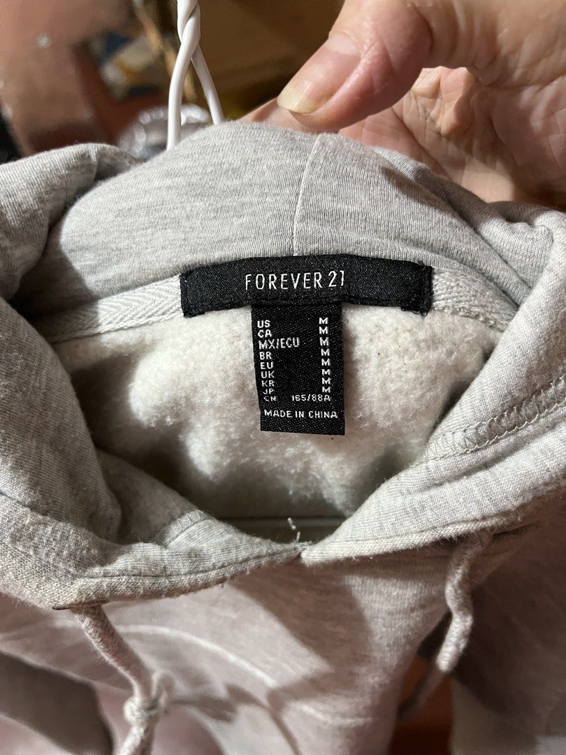 Forever 21 Grey Cropped Hoodie Size M (Category: Coats, Jackets and Outerwear) located in Marikina City. Submitted by sakura_07 (Listing ID 1469970035, Image 2). Description: - Brand: Forever 21 - Size: M - Color: Light grey - Style: Cropped hoodie with trendy corset-style seam detailing - Features: Long sleeves with ribbed cuffs, matching drawstring hood, and a soft fleece interior lining - Condition: Brand new with tag attached - Perfect for: C