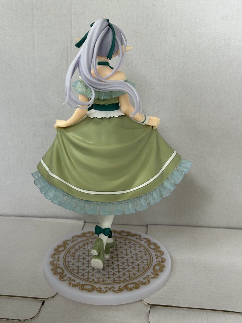 Frieren Figure Green Dress (Category: Figurines & Statues) located in President Roxas. Submitted by isserminator (Listing ID 1469955263, Image 2). Description: - Character: Frieren from the hit anime series - Outfit: Detailed green dress adorned with ruffles and bows - Appearance: Long grey-purple hair with a dark green ribbon, distinct elven ears, and green eyes - Base: White and gold decorative circular base featuring the official Frieren logo 