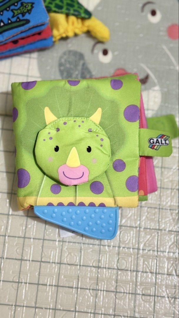 Galt Dino Tails Soft Activity Cloth Book (Category: Children's Books) located in Lucena. Submitted by jaejae___ (Listing ID 1470072240, Image 3). Description: - Brand: Galt (Dino Tails) - Type: Soft fabric interactive book for babies and toddlers - Features: Colourful dino illustrations, crinkly pages, and textured tails for sensory exploration - Bonus: Attached blue silicone teether for soothing gums - Condition: Clean, well-maintained, and read