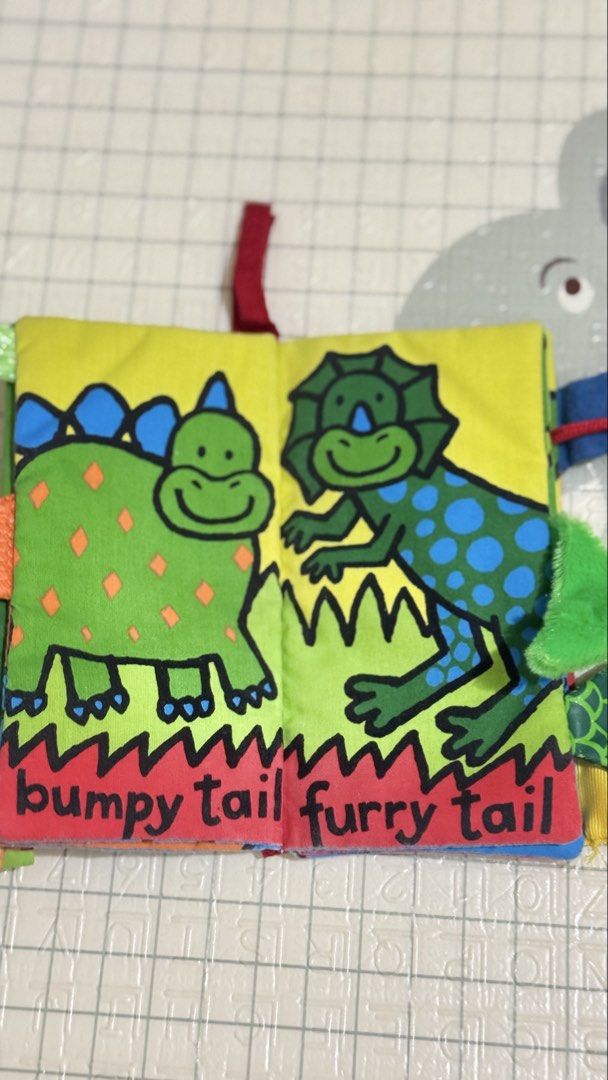 Galt Dino Tails Soft Activity Cloth Book (Category: Children's Books) located in Lucena. Submitted by jaejae___ (Listing ID 1470072240, Image 2). Description: - Brand: Galt (Dino Tails) - Type: Soft fabric interactive book for babies and toddlers - Features: Colourful dino illustrations, crinkly pages, and textured tails for sensory exploration - Bonus: Attached blue silicone teether for soothing gums - Condition: Clean, well-maintained, and read
