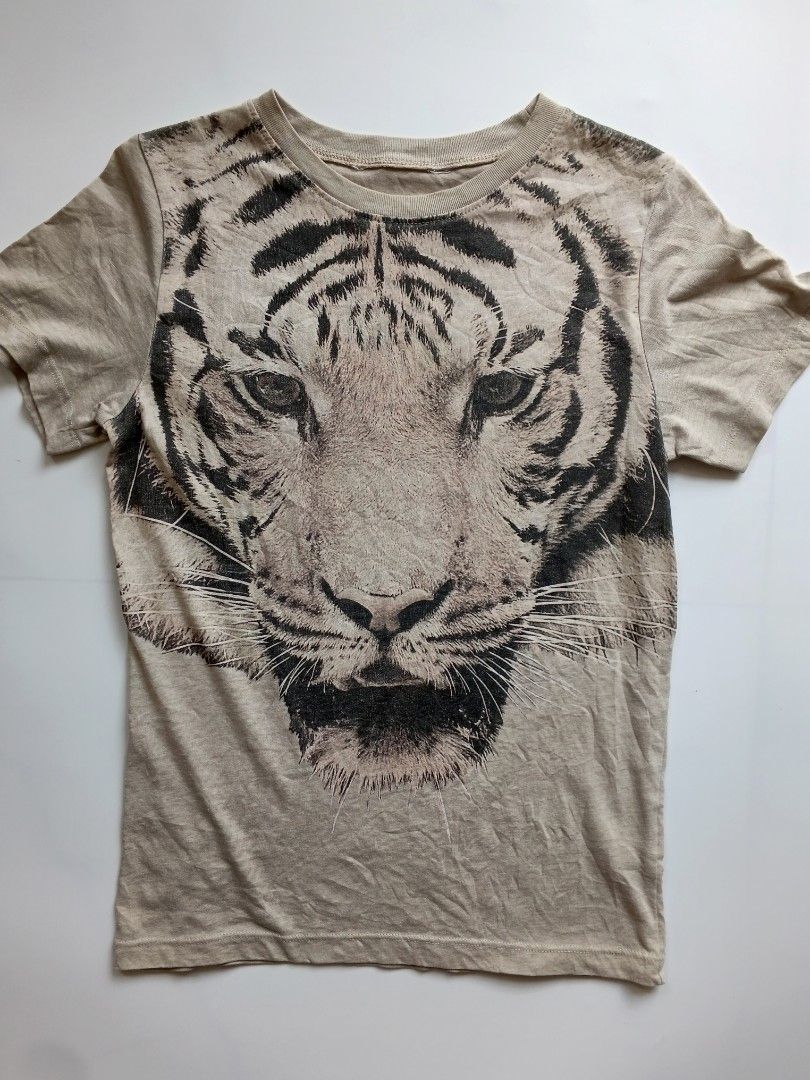 Graphic Tiger Print T-Shirt Beige (Category: Shirts) located in Batangas. Submitted by _mistystudio16 (Listing ID 1470085716, Image 2). Description: - Color: Beige - Design: Large tiger face graphic on the front chest - Neckline: Round / Crew neck - Sleeves: Short sleeves - Versatility: Easy to pair with jeans or shorts.