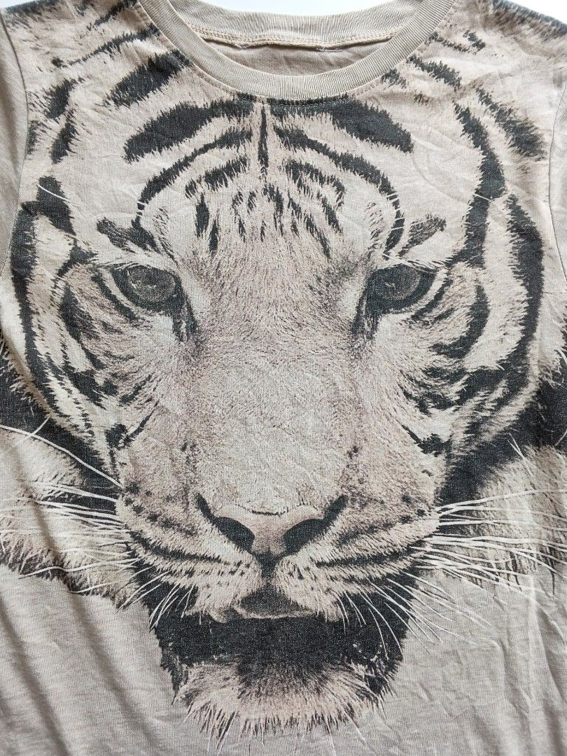 Graphic Tiger Print T-Shirt Beige (Category: Shirts) located in Batangas. Submitted by _mistystudio16 (Listing ID 1470085716, Image 3). Description: - Color: Beige - Design: Large tiger face graphic on the front chest - Neckline: Round / Crew neck - Sleeves: Short sleeves - Versatility: Easy to pair with jeans or shorts.