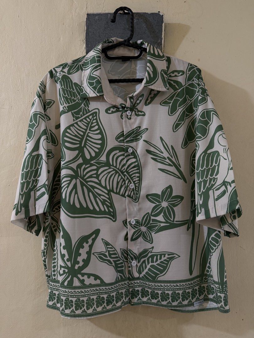 Tropical Cropped Polo (Category: Tshirts & Polo Shirts ) located in Las Pinas. Submitted by rareriroruru (Listing ID 1470052049, Image 1). Description: - Style: Relaxed resort-style short sleeve button-up - Print: Tropical parrot and jungle leaf all-over print with a patterned hem border - Color: Green and off-white - Size: Small - Length: 23.5 in - Width: 24 in - Material: Lightweight and breathable fabric - Ideal for: Summer, beach trips, and c