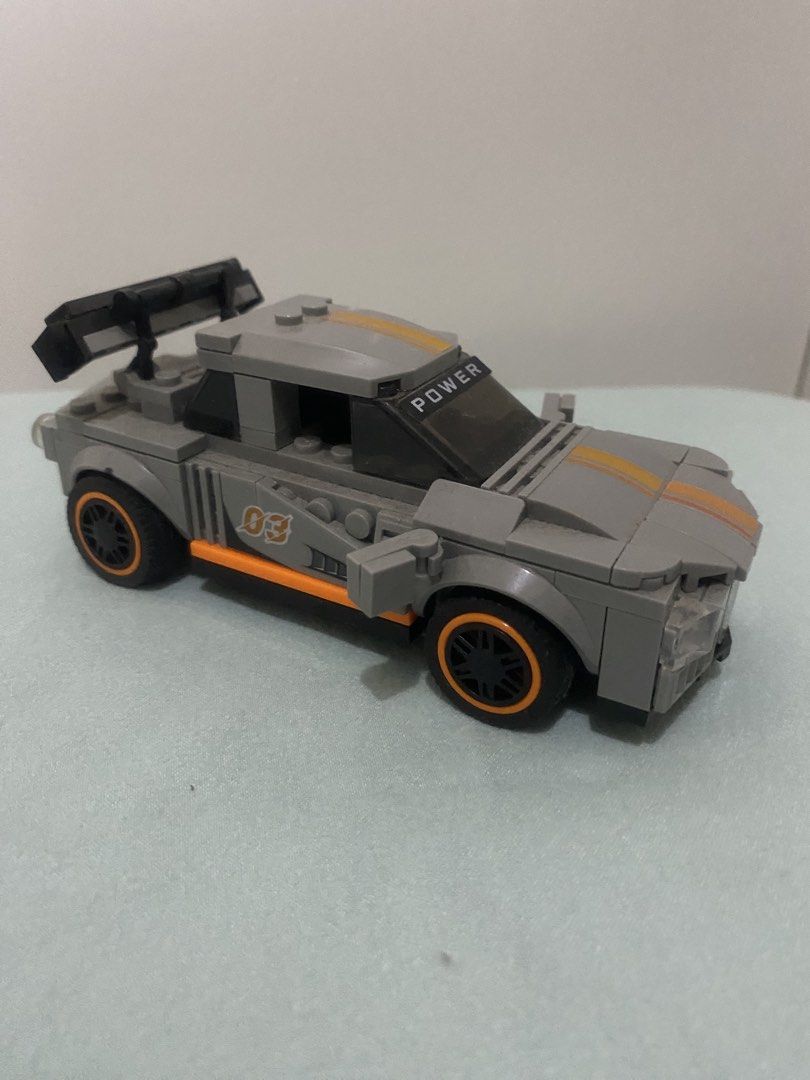 Grey Toy Racing Car Block Build (Category: Lego & Building Sets) located in Quezon City. Submitted by mg163 (Listing ID 1470041086, Image 1). Description: Grey Toy Racing Car Block Build For sale Collectible Already made, no box. As is - Pre love item - Grey building block toy race car with orange and yellow center racing stripes - Features printed number '03' and orange trim on the side doors - Equipped with a large black rear spoiler and 'POWER