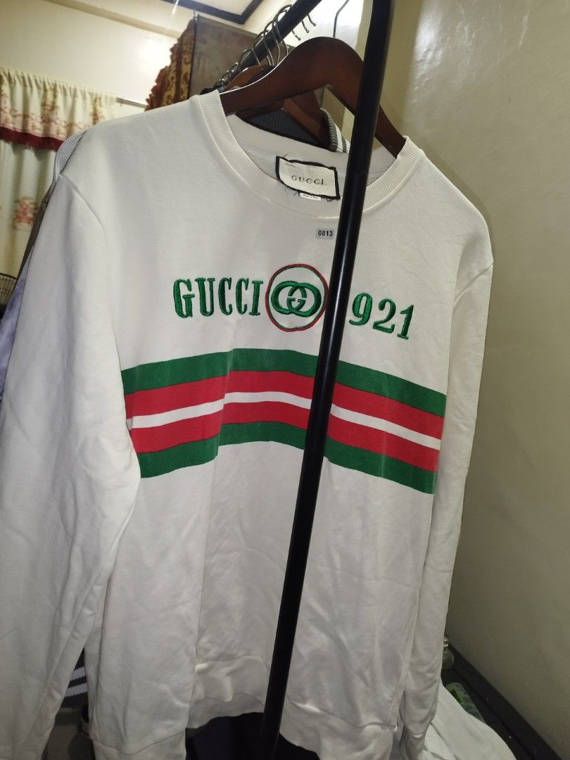 Gucci 1921 Off White Sweatshirt (Category: Coats, Jackets and Outerwear) located in Tuguegarao City. Submitted by ZeevLim (Listing ID 1470043815, Image 1). Description: - Brand: Gucci (Made in Italy) - Color: Off-white (22w 27l) - Material: Comfortable cotton fleece - Design: Green & red web stripe with 'GUCCI 1921' embroidery and interlocking G logo - Style: Classic crewneck with ribbed collar, cuffs, and hem - Condition: Pre-owned with a few fa