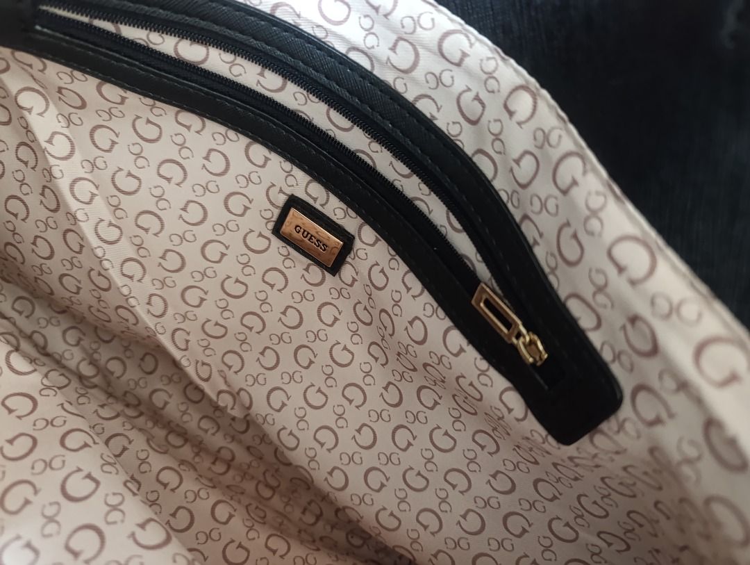 Guess Black Tote Bag with Gold Hardware (Category: Tote Bags) located in Malolos. Submitted by vintagefat (Listing ID 1469963211, Image 2). Description: - Brand: Guess - Color: Black with gold-tone hardware - Material: Textured exterior with cream logo-patterned interior lining - Closure: Front strap clasp and main zip closure - Pockets: Interior zip pocket with branded pull - Condition: Clean interior and exterior, ready to use.