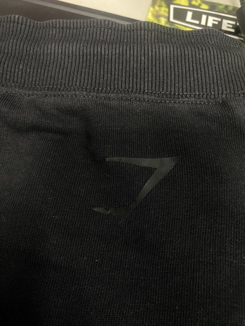 Gymshark Black Shorts Size M (Category: Shorts) located in Manila. Submitted by kuya_moto (Listing ID 1470029773, Image 3). Description: - Brand: Gymshark - Color: Black - Size: Medium - Waist: Elastic with adjustable drawstring - Design: Large Gymshark branding and mesh panel down the side leg - Details: Small logo print near front pocket - Origin: Made in Madagascar.