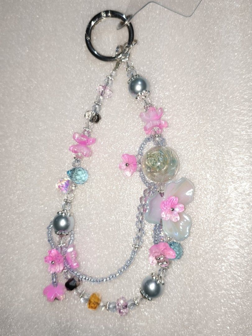 Handmade Beaded Phone Charm / Keychain Assortment (Category: Handmade Craft) located in Caloocan City. Submitted by books_and_beads (Listing ID 1470081483, Image 3). Description: - Handmade beaded charm with unique color combinations - Features cute flower, butterfly, and colorful bead accents: · Left Chain: A vibrant, maximalist ocean theme. It features bubblegum pink flower and butterfly charms alongside a large seafoam green glass disc, a brig