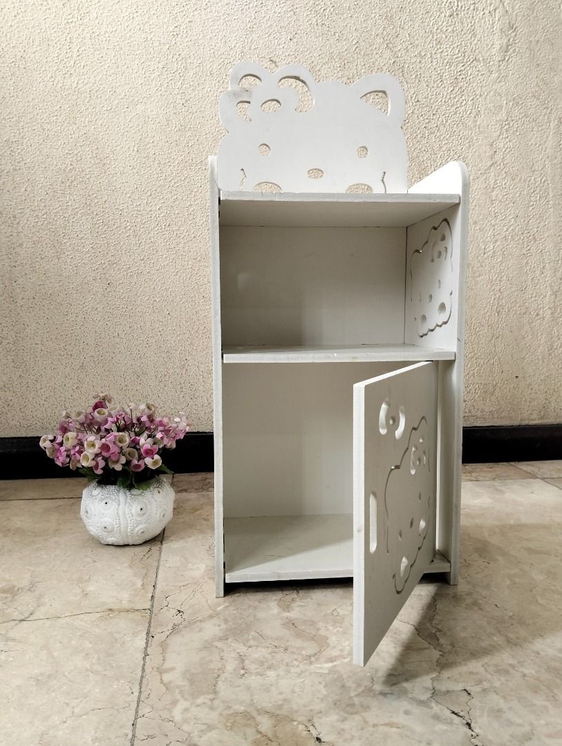 Hello Kitty White Wooden Storage Shelf with Cabinet (Category: Shelves, Cabinets & Racks) located in Binan City. Submitted by croti_by_juliechi (Listing ID 1470138726, Image 1). Description: - White wooden storage shelf with adorable Kitty cutouts - Features an open upper compartment and lower cabinet with swinging door - Cute decorative cutouts on the side panels - Solid and sturdy build, perfect for kids' rooms - Compact size fits nicely on the