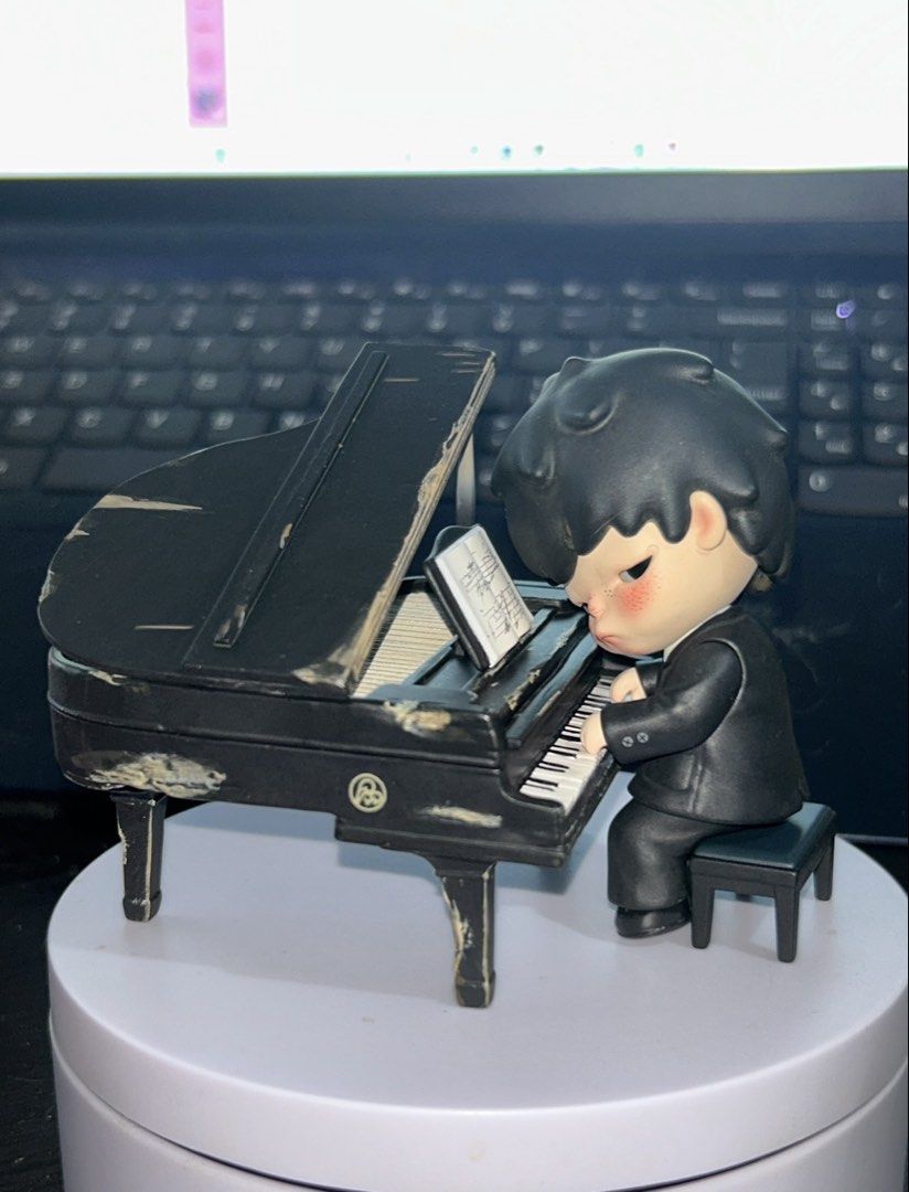Hirono Pianist (Category: Designer & Blind Box Toys) located in Manila. Submitted by donnaburde79462 (Listing ID 1470073199, Image 1). Description: - Art toy figure featuring a boy in a sleek black suit playing the piano - Includes a matching black grand piano with a cool distressed paint effect on edges and legs - Comes with a separate black piano bench and tiny sheet music on the stand - Highly detailed sculpt with adorable rosy cheeks and dark