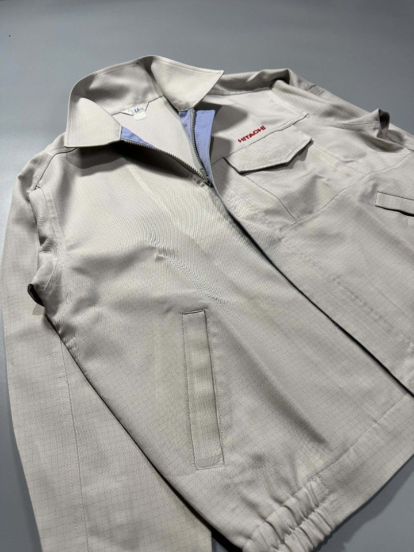 Hitachi Corporate Work Jacket Light Grey Utility Outerwear (Category: Coats, Jackets and Outerwear) located in Manila. Submitted by whoego (Listing ID 1470122615, Image 3). Description: - Brand: Hitachi Length: 27.5 inches Width: 25.2 inches Shoulders: 21.3 inches Sleeves: 10.5 inches - Color: Light grey with blue inner collar and red embroidered chest logo - Style: Zip-up work jacket with stand collar and elasticated back hem - Pockets: Front fl