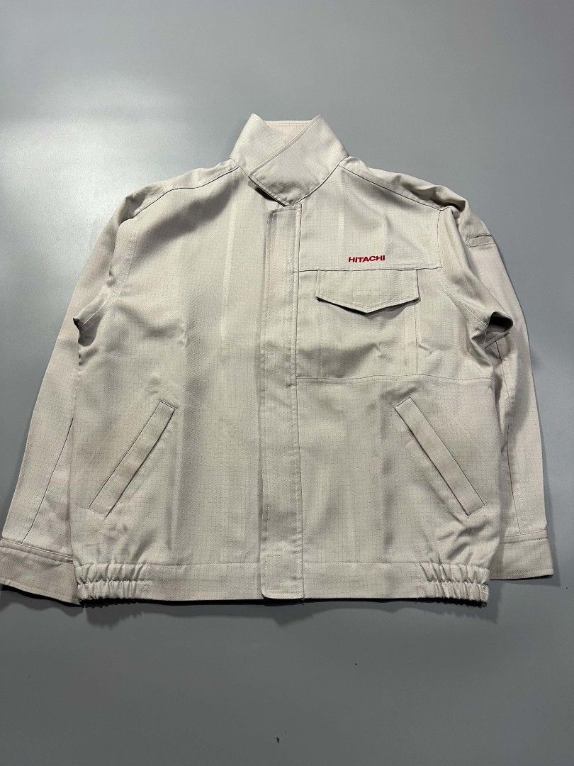 Hitachi Corporate Work Jacket Light Grey Utility Outerwear (Category: Coats, Jackets and Outerwear) located in Manila. Submitted by whoego (Listing ID 1470122615, Image 1). Description: - Brand: Hitachi Length: 27.5 inches Width: 25.2 inches Shoulders: 21.3 inches Sleeves: 10.5 inches - Color: Light grey with blue inner collar and red embroidered chest logo - Style: Zip-up work jacket with stand collar and elasticated back hem - Pockets: Front fl