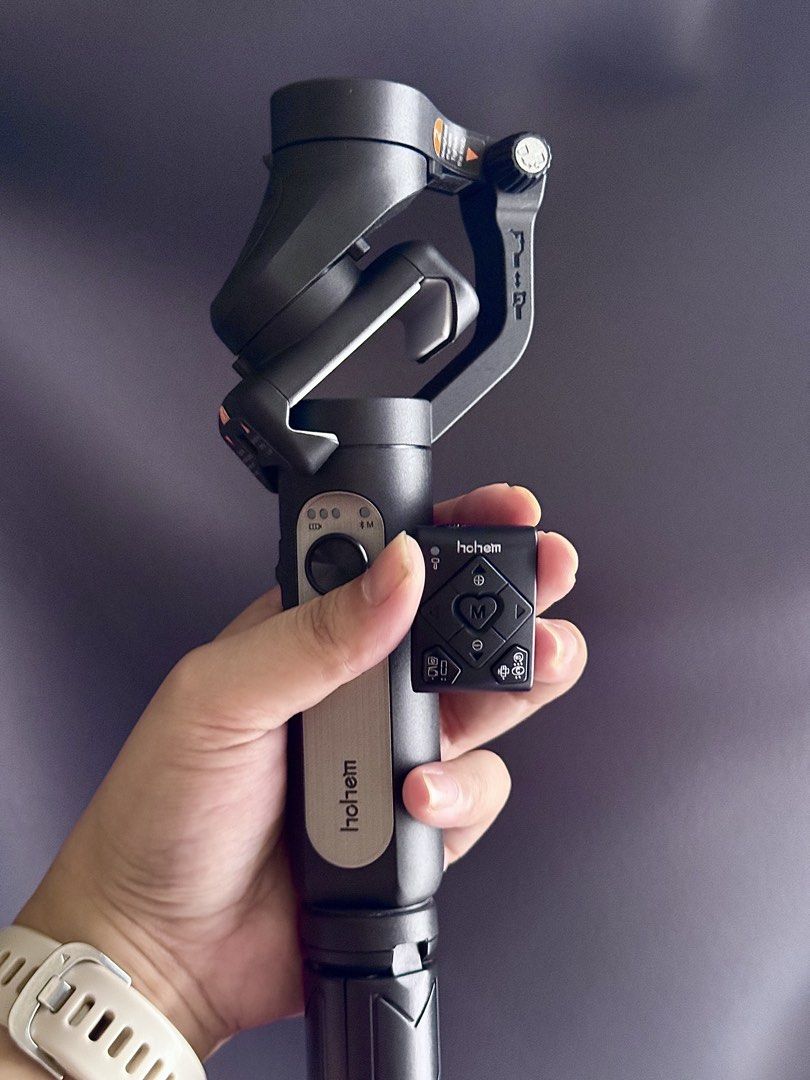 Hohem iSteady Mobile Gimbal Stabilizer with Remote (Category: Gimbals & Stabilizers ) located in Manila. Submitted by kbeefinds (Listing ID 1469984794, Image 3). Description: - Brand: Hohem Smartphone Gimbal Stabilizer - Color: Sleek black with a compact, foldable design - Features: Integrated handle and sturdy built-in tripod base - Remote: Includes a detachable magnetic remote control with D-pad and function buttons - Battery & Charging: Built-