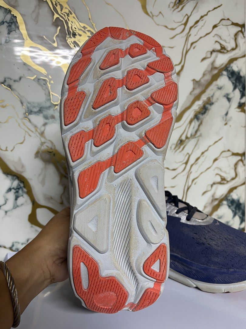 Hoka One One Running Shoes Blue Silver (Category: Sneakers) located in Manila. Submitted by lkiss13 (Listing ID 1470074385, Image 3). Description: - Brand: Hoka - Color: Navy blue with large silver branding and metallic silver panels - Cushioning: Thick white and blue cushioned midsole - Outsole: Orange and white rubber with moderate tread wear - Condition: Uppers show slight dirt marks from previous runs - Usage: Great daily trainers with plenty