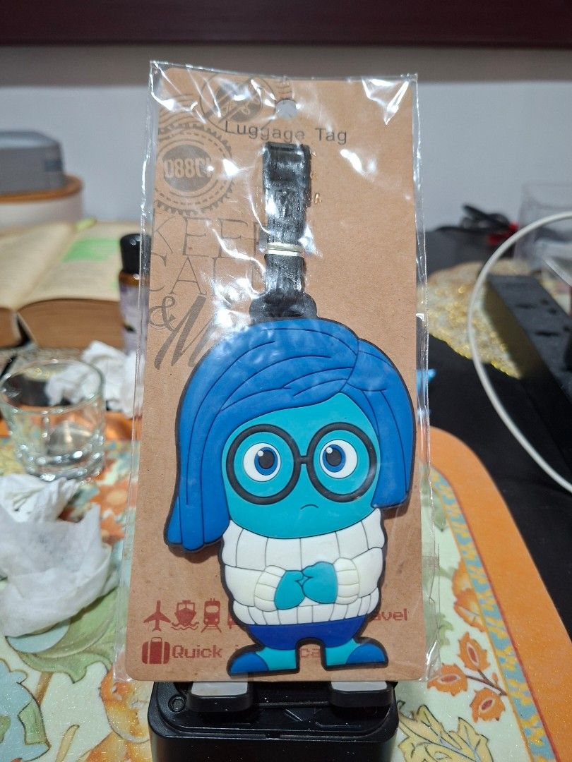 Inside Out Sadness Silicone Luggage Tag (Category: Luggage) located in Bulacan. Submitted by rafaesarisari (Listing ID 1469991895, Image 1). Description: - Character: Sadness from Disney Pixar's Inside Out - Material: High-quality molded silicone - Design: Bright blue hair, glasses, and white sweater - Attachment: Secure black strap with a buckle fastener - Condition: Brand new, sealed in original packaging - Ideal for: Luggage, backpacks, and Di