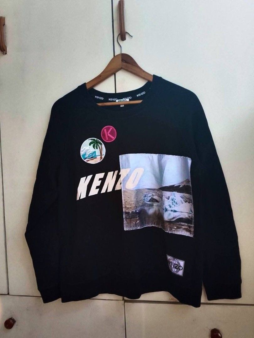 Kenzo Paris Black Sweatshirt Patch Design Size L (Category: Coats, Jackets and Outerwear) located in Bogo. Submitted by algarme2018 (Listing ID 1470054498, Image 1). Description: - Brand: Kenzo Paris - Size: Large - Dimes: W21 * L25 - Color: Black - Material: Comfortable cotton blend - Origin: Made in Portugal - Design: Graphic patches (palm tree, glacier, pink 'K' logo) with bold 'KENZO' chest lettering - Details: Ribbed collar, cuffs, and hem w
