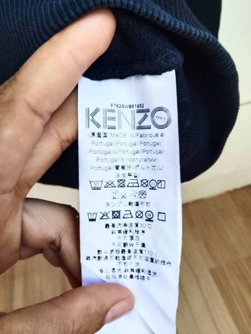 Kenzo Paris Black Sweatshirt Patch Design Size L (Category: Coats, Jackets and Outerwear) located in Bogo. Submitted by algarme2018 (Listing ID 1470054498, Image 3). Description: - Brand: Kenzo Paris - Size: Large - Dimes: W21 * L25 - Color: Black - Material: Comfortable cotton blend - Origin: Made in Portugal - Design: Graphic patches (palm tree, glacier, pink 'K' logo) with bold 'KENZO' chest lettering - Details: Ribbed collar, cuffs, and hem w
