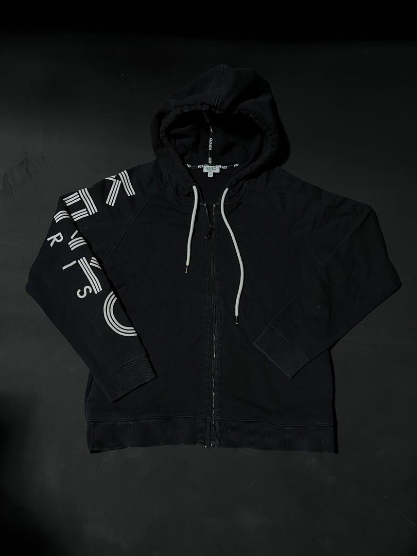 Kenzo Paris Black Zip-Up Hoodie (Category: Coats, Jackets and Outerwear) located in Andop. Submitted by outclickz_00 (Listing ID 1470120568, Image 1). Description: - Brand: Kenzo Paris - Style: Zip-up hoodie - Color: Black with bold white logo graphics on the right sleeve - Size: Medium 20/25 - Features: Drawstring hood with branded tape details, full front zipper, ribbed cuffs and hem, and two front pockets - Condition: Excellent, interior tags 