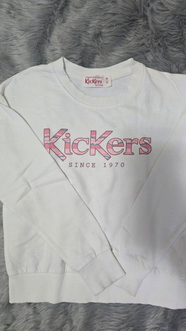 Kickers White Sweatshirt 4Y 5Y (Category: Babies & Kids Fashion) located in Cabanatuan. Submitted by belle_1013 (Listing ID 1470026476, Image 2). Description: - Brand: Kickers - Size: 4Y to 5Y - Color: Clean white with bold pink logo and 'SINCE 1970' text - Details: Classic ribbed crew neckline, cuffs, and hem - Condition: Excellent, ready to wear.