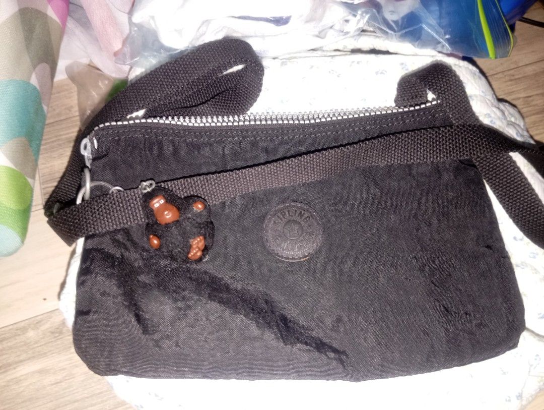 Kipling Black Crossbody Bag with Monkey Keychain (Category: Cross-body Bags) located in Binangonan. Submitted by lalamo_collection (Listing ID 1470051326, Image 1). Description: - Brand: Kipling - Color: Classic Black - Material: Signature crinkled nylon with silver-tone hardware - Closure: Secure zippered main compartment - Strap: Long adjustable crossbody strap for comfortable wear - Details: Iconic round rubber Kipling logo patch on the front 