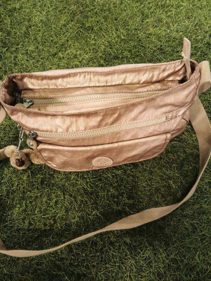 Kipling Rose Gold Nylon Crossbody Bag (Category: Cross-body Bags) located in Lucena. Submitted by jmjm31 (Listing ID 1470082376, Image 2). Description: - Brand: Kipling - Color: Rose Gold - Material: Durable Nylon - Condition: Brand new with tags tucked in pocket, clean interior lining - Features: Multiple exterior zip compartments, spacious main interior with slip pockets - Extras: Secure key leash and signature furry monkey keychain - Strap: Lo