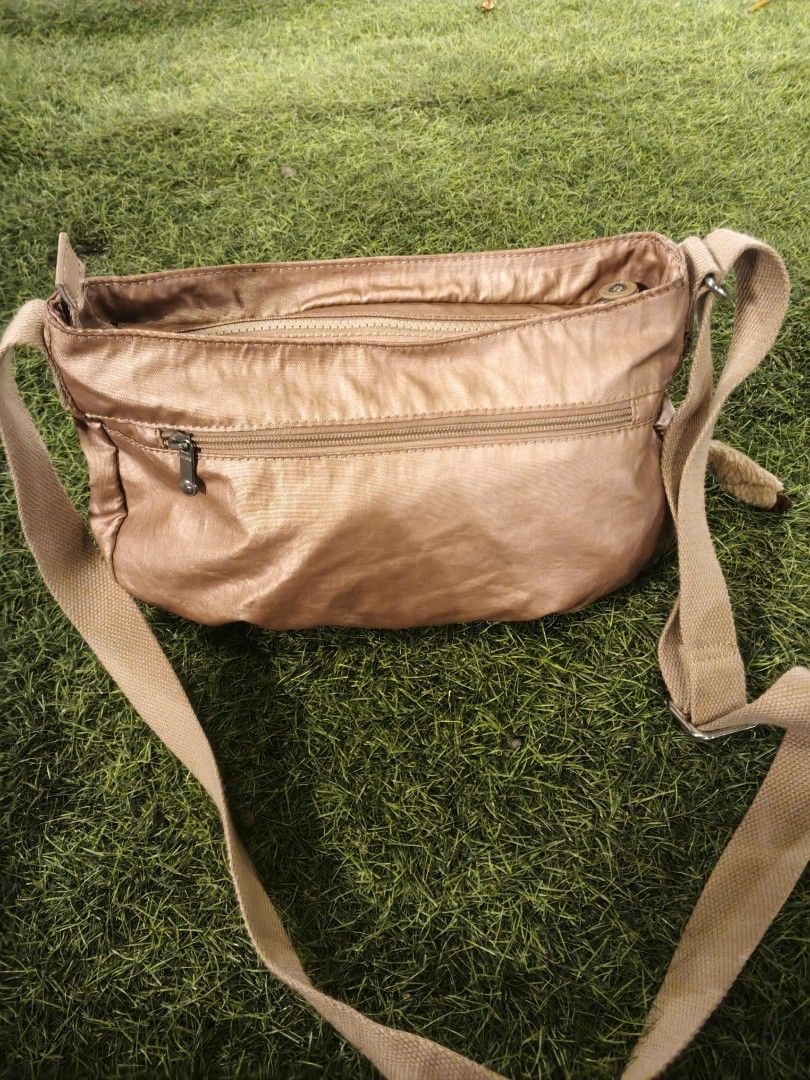 Kipling Rose Gold Nylon Crossbody Bag (Category: Cross-body Bags) located in Lucena. Submitted by jmjm31 (Listing ID 1470082376, Image 3). Description: - Brand: Kipling - Color: Rose Gold - Material: Durable Nylon - Condition: Brand new with tags tucked in pocket, clean interior lining - Features: Multiple exterior zip compartments, spacious main interior with slip pockets - Extras: Secure key leash and signature furry monkey keychain - Strap: Lo