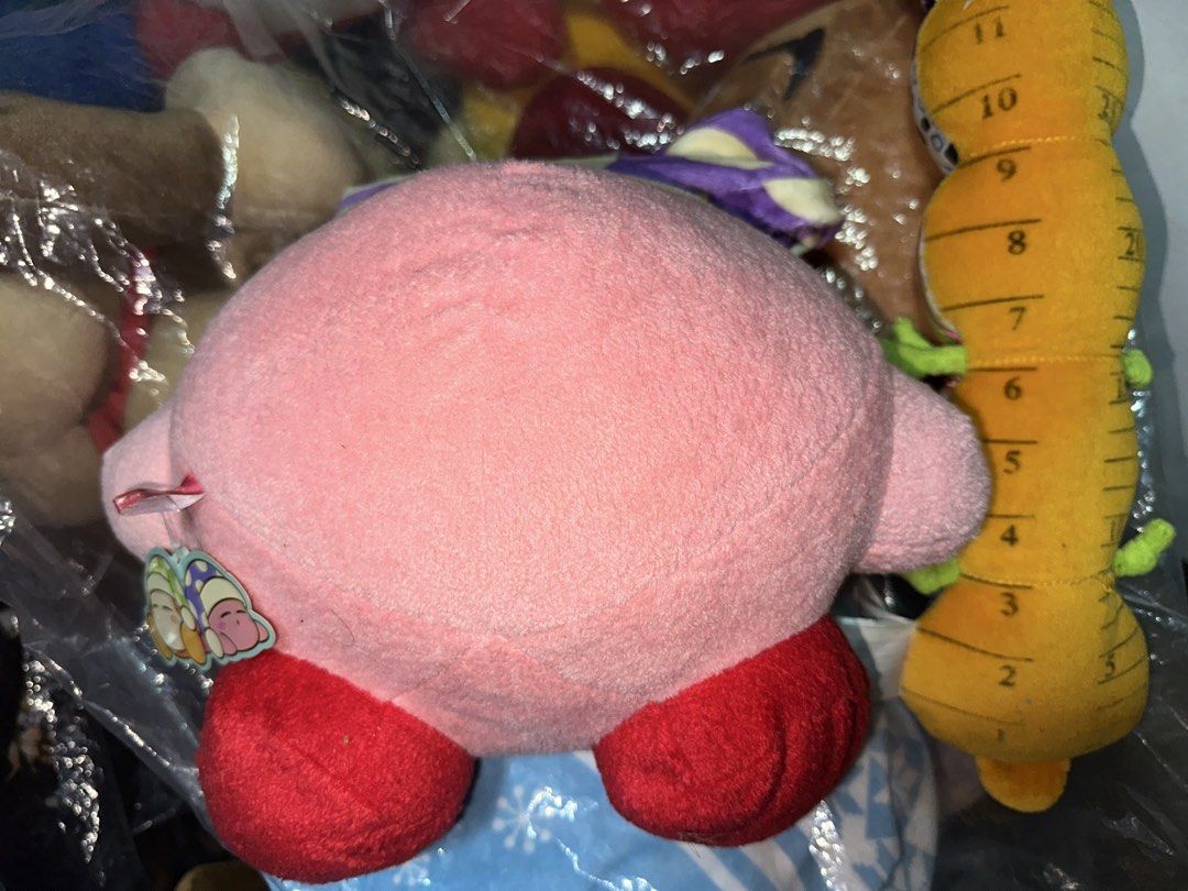 Kirby with Sleeping Cap with papertag (Category: Plushies & Soft Toys) located in Pasig City. Submitted by katplush_superlove (Listing ID 1470043021, Image 2). Description: - Official-style cute Kirby plush figure in a sleeping pose - Features a cozy purple and yellow patterned sleeping cap with a pom-pom - Made with ultra-soft, huggable pink fabric with embroidered closed eyes and red feet - Tag attached near the side, great for collectors - Per