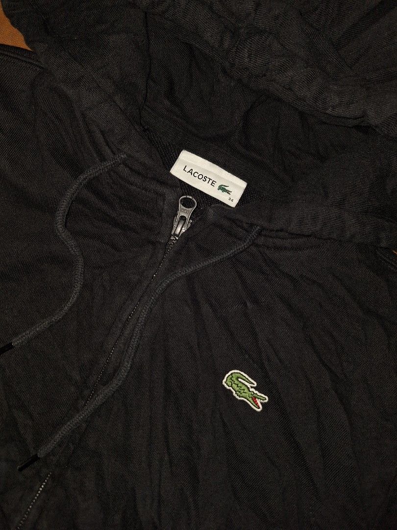 Lacoste Black Zip-Up Hoodie (Category: Coats, Jackets and Outerwear) located in Bago City. Submitted by thriftgarments0121 (Listing ID 1469995104, Image 2). Description: - Brand: Lacoste - Color: Classic Black - Material: Comfortable cotton blend - Design: Iconic embroidered green crocodile logo on the chest - Features: Standard front zip closure, adjustable drawstring hood, ribbed cuffs and hem - Mode of Payment: GCash, BPI, or Bank Transfer - S