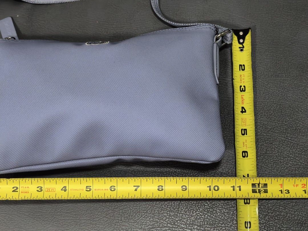 Lacoste Blue Crossbody Bag (Category: Cross-body Bags) located in Cagayan de Oro. Submitted by pootx (Listing ID 1470090813, Image 2). Description: - Brand: Lacoste - Style: Crossbody bag - Color: Light blue - Material: Textured PVC with fabric interior lining - Hardware: Silver-tone with adjustable strap - Closure: Top zipper with branded pull tab - Accents: Iconic crocodile logo applique and repeating Lacoste wordmark on interior trim - Dimensi