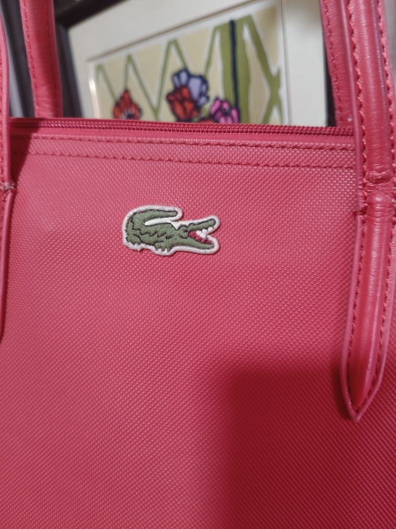 Lacoste Red Tote Bag (Category: Tote Bags) located in Bulacan. Submitted by pesa_39 (Listing ID 1469979506, Image 2). Description: - Brand: Lacoste - Color: Red - Material: Durable textured nylon - Closure: Secure zip top - Design: Dual shoulder straps with iconic embroidered green crocodile logo - Interior: Spacious everyday tote bag - Condition: Minor wear near strap base stitches -Maganda, authentic Lacoste tote bag.