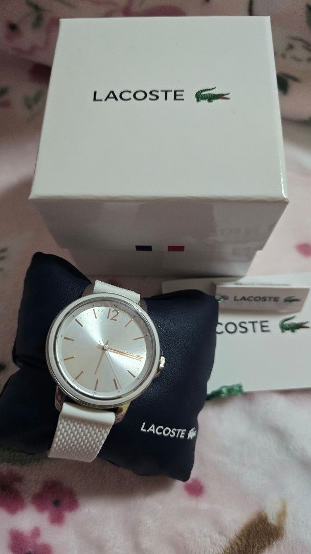 Lacoste White Watch 2001197 (Category: Luxury Watches) located in Quezon City. Submitted by impdc1130 (Listing ID 1470132818, Image 1). Description: White Lacoste watch, model 2001197. Silver sunray dial with rose gold accents and a prominent 12 o'clock marker. White textured silicone strap. Original white and navy presentation box included with store tags attached. Unworn condition, tags still on..