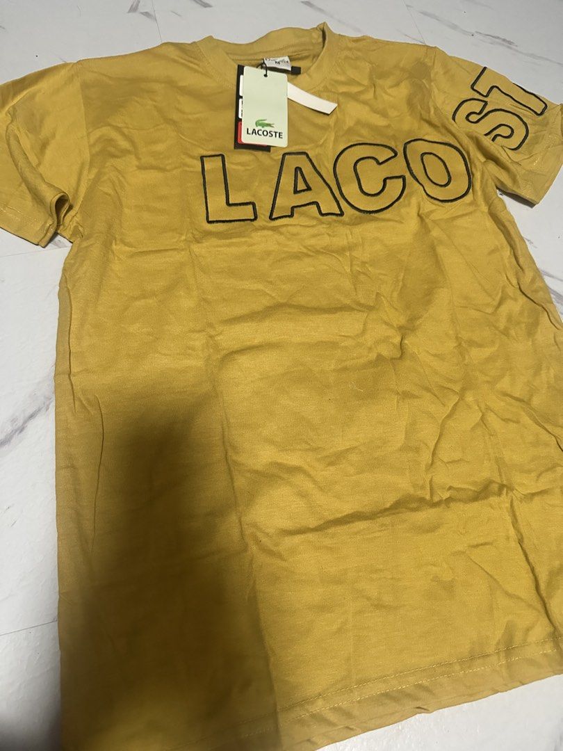 Lacoste Yellow T-Shirt with Tag (Category: Tshirts & Polo Shirts ) located in Manila. Submitted by tipidfinds888 (Listing ID 1470017347, Image 1). Description: - Brand: Lacoste - Condition: Brand new with paper tag attached - Color: Bright yellow with bold black lettering - Design: Crew neck, short sleeves, lettering extends to the left sleeve - Fit & Material: Regular fit, soft cotton feel - Style: Casual wear.