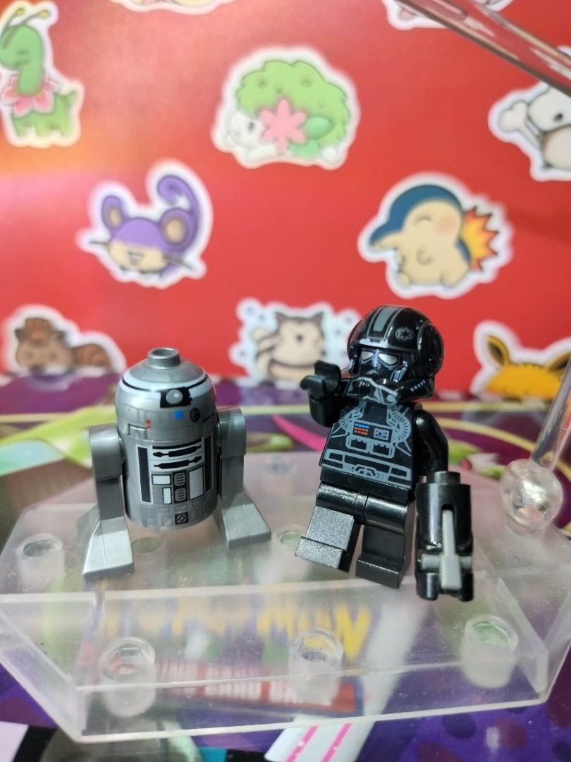 LEGO Star Wars Imperial V-Wing Pilot & R2-Q2 Droid Bundle (Category: Lego & Building Sets) located in San Antonio. Submitted by lansbitshop (Listing ID 1470092812, Image 1). Description: Minifigure: Genuine LEGO Imperial V-wing Pilot (ID: sw0304). Features a detailed black flight suit torso print with control panels, grey utility stripes, and a specialized Imperial pilot helmet insignia. Droid: Includes the authentic matching silver and dark char