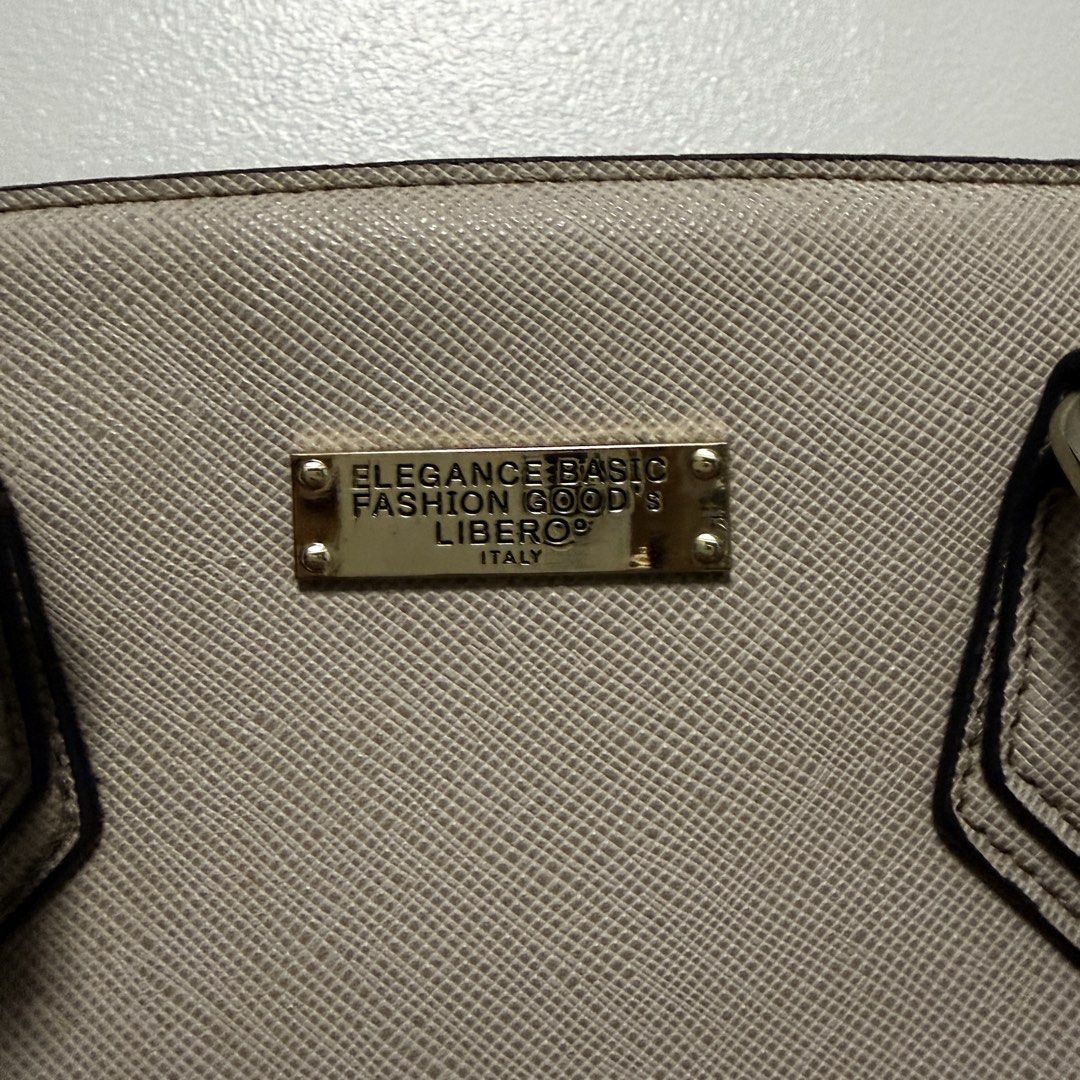 Libero Elegance Basic Fashion Goods Handbag (Category: Luxury Bags & Wallets) located in Tanza. Submitted by iamdhana (Listing ID 1469988390, Image 2). Description: - You can search the brand. Issue: Lightly used but the gold hardware ay mejo tarnished na and the long strap is mejo maluwag na yung clasp :) Brand: Libero - Color: Elegant beige with contrasting black edge detailing on handles - Material: Durable Saffiano texture faux leather - Hard