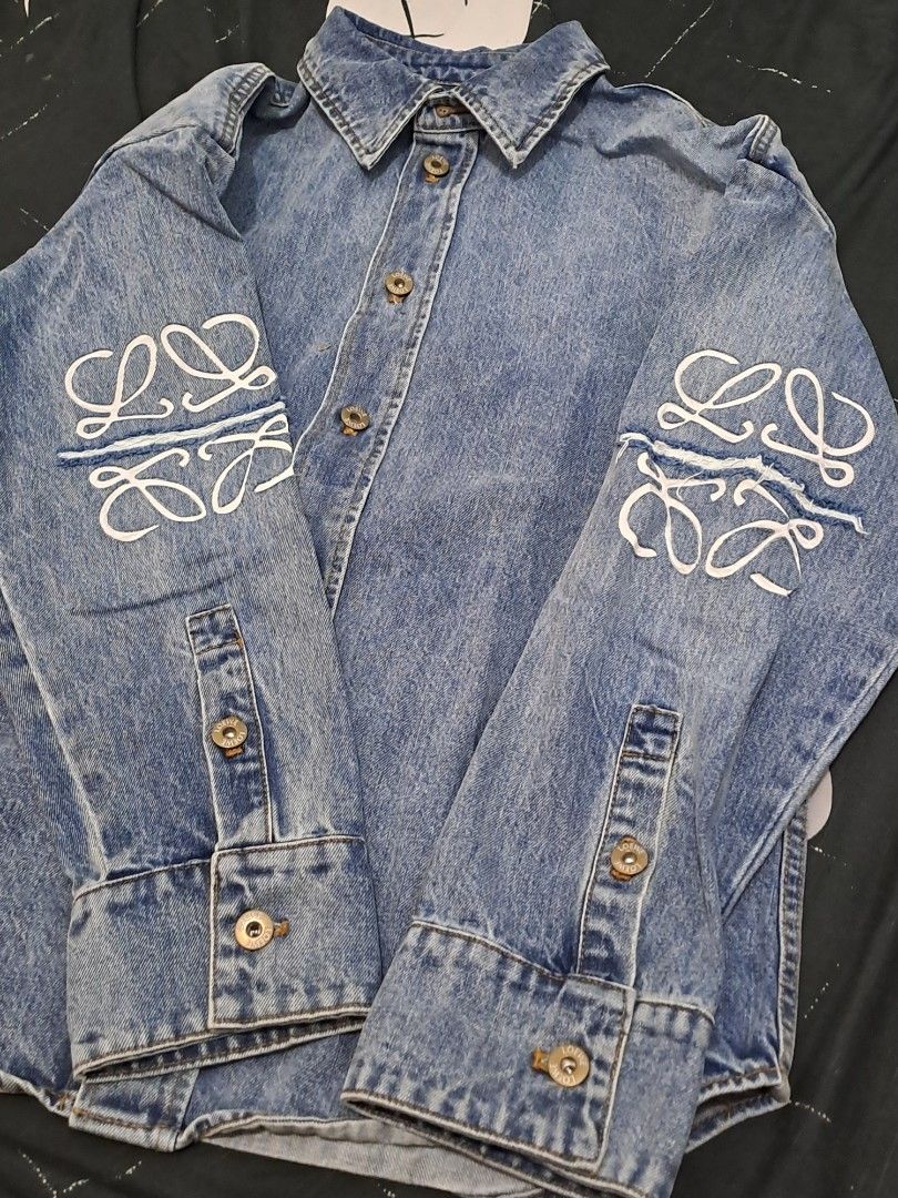 Loewe Anagram Overshirt Denim Shirt Jacket (Category: Luxury Apparel) located in Puerto Princesa. Submitted by jercksthriftph (Listing ID 1469957131, Image 3). Description: - Brand: Loewe - Size: 36 oversized fits large to XL - Style: Oversized denim shirt jacket / overshirt - Color: Classic blue mid-wash - Details: White Anagram embroidery, distressed spliced arm details, branded metal buttons, pointed collar, and buttoned cuffs - Fit: Oversized