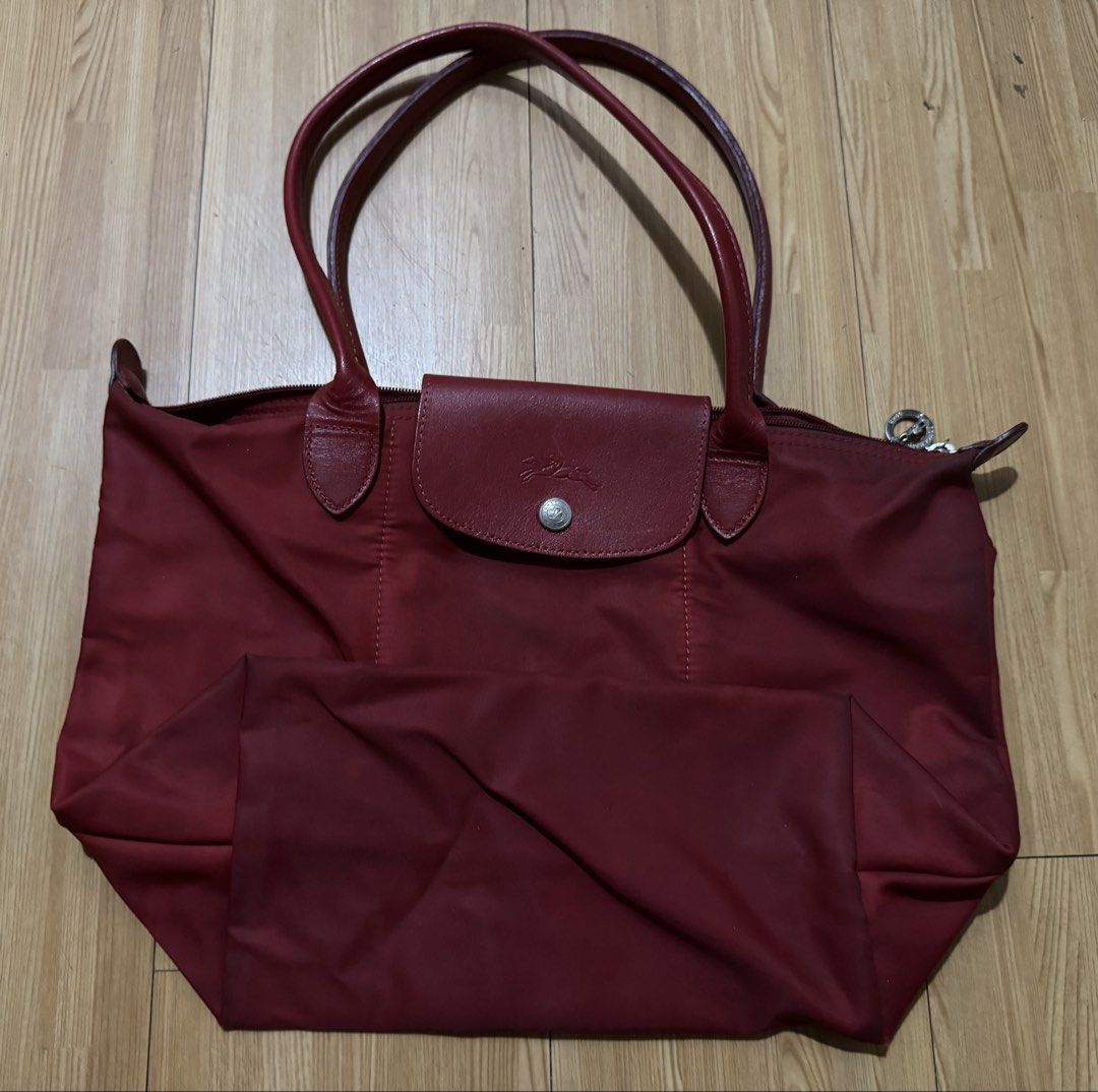 LONGCHAMP Planetes Red Long Handle (Category: Luxury Bags & Wallets) located in Pasig City. Submitted by lurvethrift (Listing ID 1470087069, Image 1). Description: - Authentic red Longchamp tote bag - Double leather handles with zip-top closure - Signature embossed horse logo on front leather flap - Silver-toned hardware with 1948 branding on zipper pull - Convenient interior open slip pocket - Condition: Shows signs of wear and staining inside a