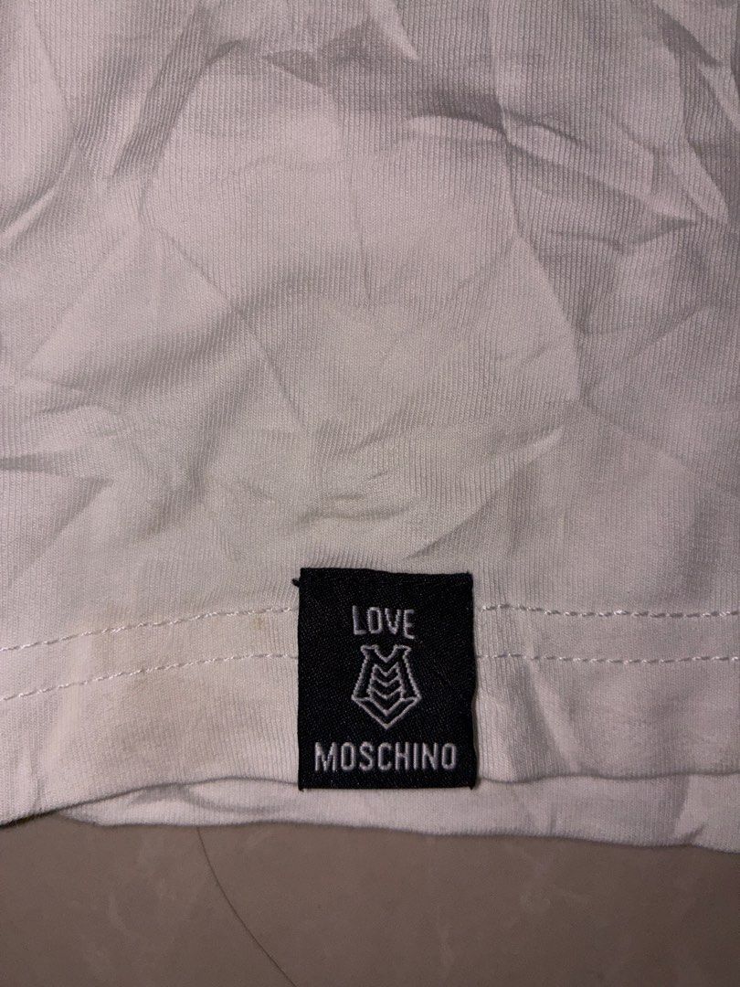 Love Moschino White T-Shirt with Triangle Patch (Category: Shirts) located in Placer. Submitted by talaalond61563 (Listing ID 1470089615, Image 2). Description: - Brand: Love Moschino - Color: Crisp white - Fit: Standard fit, short sleeves - Size: XL - Material: Comfortable, high-quality cotton - Details: Multicolor triangular embroidered logo patch on the chest, branded fabric labels at the hem and lower side seam - Condition: Excellent, clean w