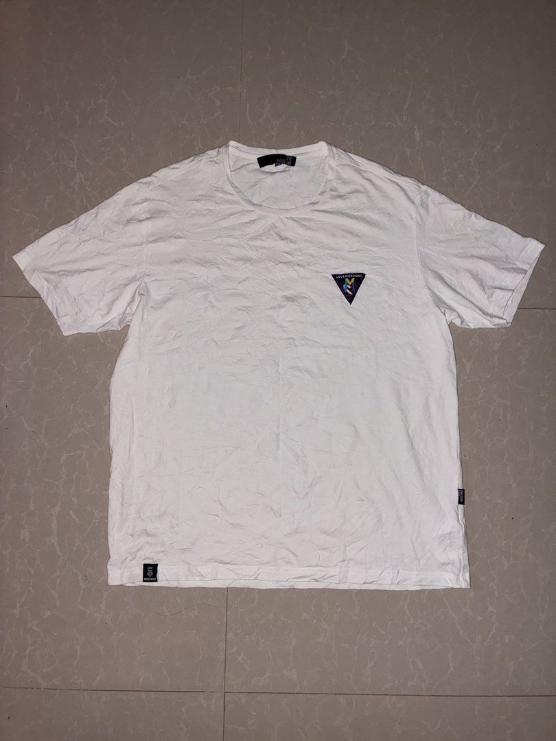 Love Moschino White T-Shirt with Triangle Patch (Category: Shirts) located in Placer. Submitted by talaalond61563 (Listing ID 1470089615, Image 1). Description: - Brand: Love Moschino - Color: Crisp white - Fit: Standard fit, short sleeves - Size: XL - Material: Comfortable, high-quality cotton - Details: Multicolor triangular embroidered logo patch on the chest, branded fabric labels at the hem and lower side seam - Condition: Excellent, clean w