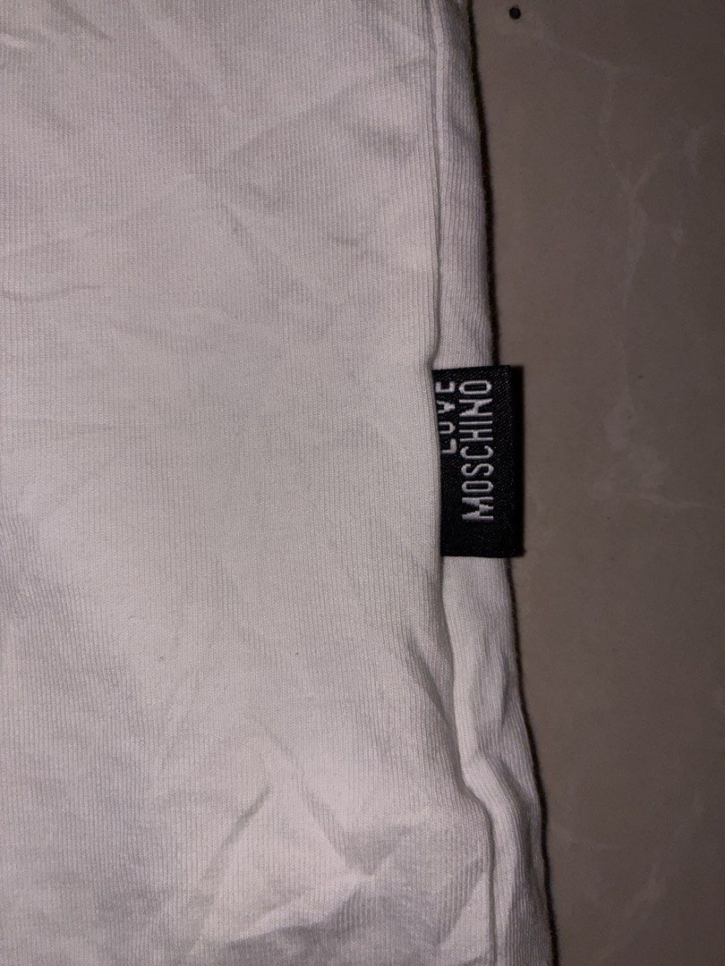 Love Moschino White T-Shirt with Triangle Patch (Category: Shirts) located in Placer. Submitted by talaalond61563 (Listing ID 1470089615, Image 3). Description: - Brand: Love Moschino - Color: Crisp white - Fit: Standard fit, short sleeves - Size: XL - Material: Comfortable, high-quality cotton - Details: Multicolor triangular embroidered logo patch on the chest, branded fabric labels at the hem and lower side seam - Condition: Excellent, clean w