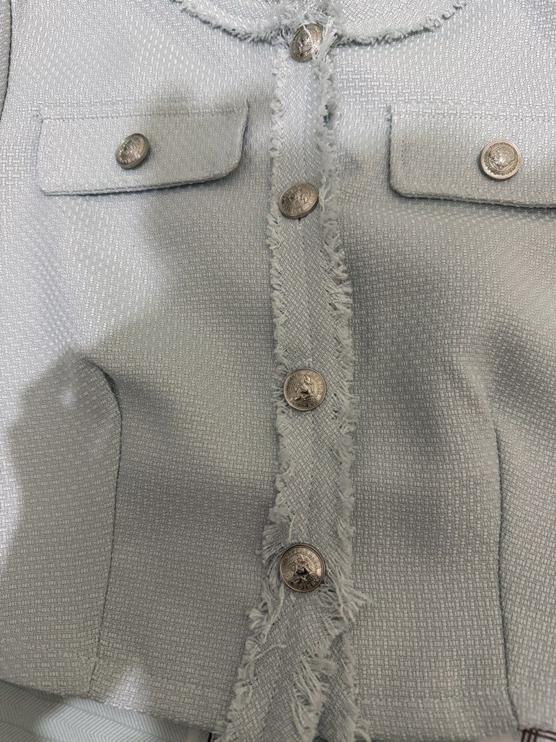 Lovito Light Blue Tweed Short Sleeve Jacket (Category: Coats, Jackets and Outerwear) located in Manila. Submitted by misskendrapreloved (Listing ID 1470099825, Image 2). Description: - Brand: Lovito - Color: Light blue - Style: Short sleeve cropped tweed jacket - Neckline: Round neck with frayed trim edges - Closure: Front button closure with silver ornate buttons - Pockets: Two chest pockets with button flaps - Fabric: Textured tweed throughout 