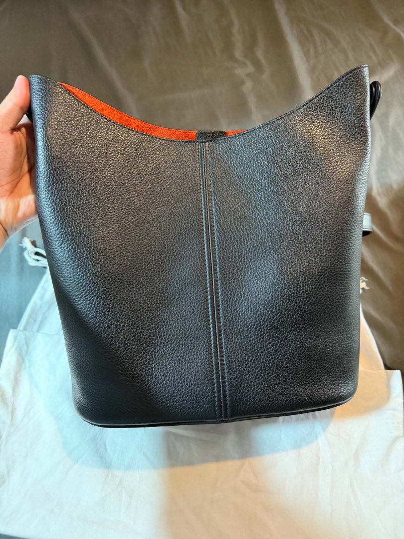Maison Margiela Black Leather Bucket Bag (Category: Luxury Bags & Wallets) located in Manila. Submitted by dalandansoy (Listing ID 1469974974, Image 3). Description: - Brand: Maison Margiela - Style: Bucket bag in black grained leather - Interior: Contrast vibrant orange - Details: Iconic four white stitches on front - Strap: Adjustable shoulder strap included - Inclusion: Dust bag - Condition: Clean structure with minimal wear overall.