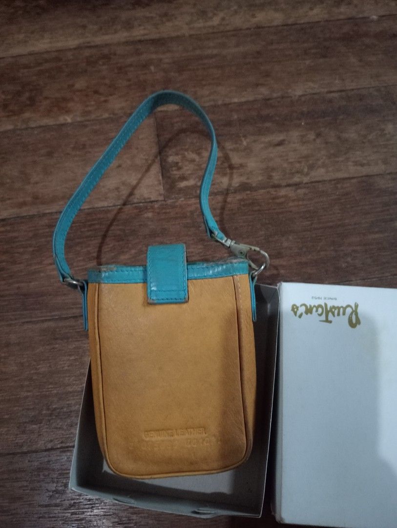 Manel's Genuine Leather Mini Pouch Bag with Strap (Category: Cross-body Bags) located in Makati City. Submitted by YSL80022 (Listing ID 1470036363, Image 2). Description: - Brand: Manel's - Color: Tan body with bright blue trim and matching strap - Material: Genuine leather (stamp on the back) - Closure: Flap closure with metal clasps on the strap - Details: Embossed Manel's logo on the front - Inclusion: Comes with an original white Rustan's box