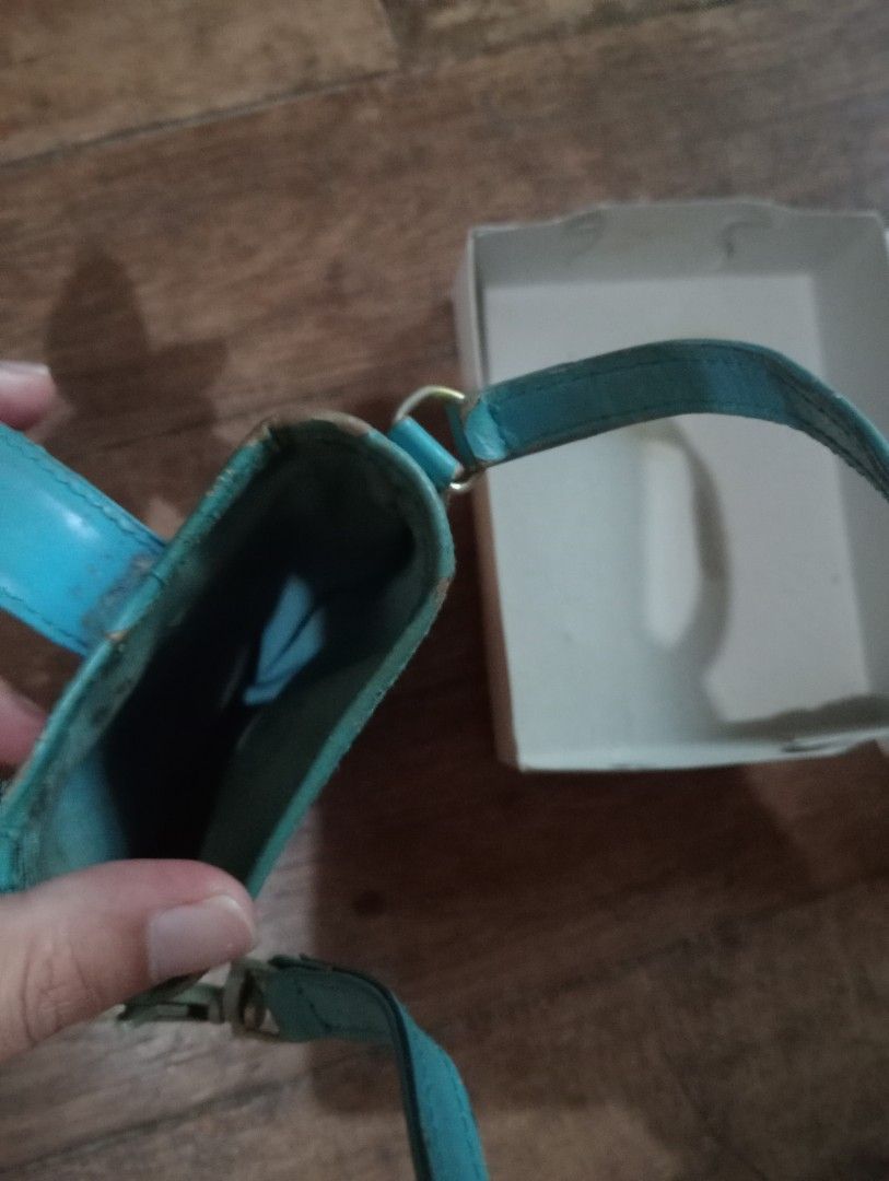 Manel's Genuine Leather Mini Pouch Bag with Strap (Category: Cross-body Bags) located in Makati City. Submitted by YSL80022 (Listing ID 1470036363, Image 3). Description: - Brand: Manel's - Color: Tan body with bright blue trim and matching strap - Material: Genuine leather (stamp on the back) - Closure: Flap closure with metal clasps on the strap - Details: Embossed Manel's logo on the front - Inclusion: Comes with an original white Rustan's box