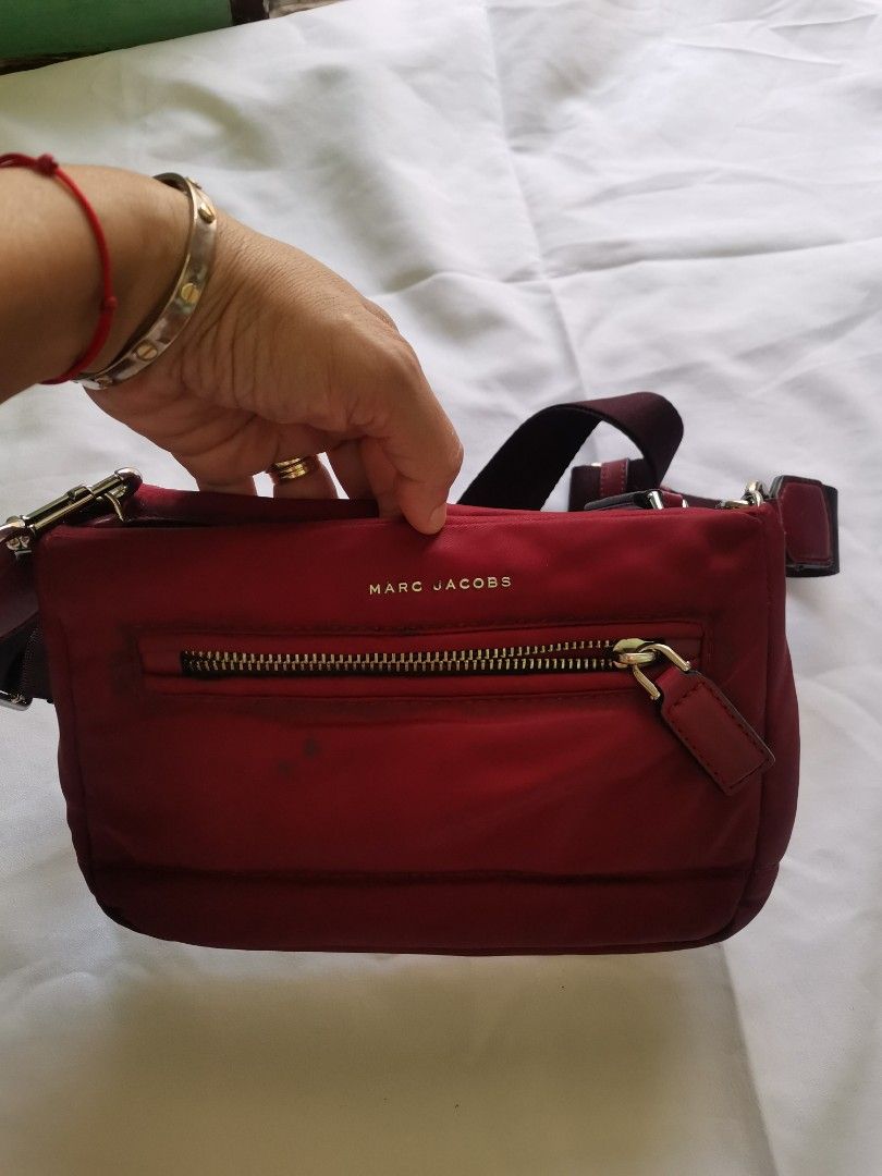 Marc Jacobs red nylon crossbody bag (Category: Luxury Bags & Wallets) located in Daet. Submitted by prelovedatbp (Listing ID 1470008511, Image 3). Description: - Authentic Marc Jacobs crossbody bag in vibrant red nylon - Elegant gold hardware accents and front zip pocket - Adjustable dark strap with chic leather trim - Sturdy zippers and smooth-working metal clasps - Clean overall shape with minor marks near the front zipper.