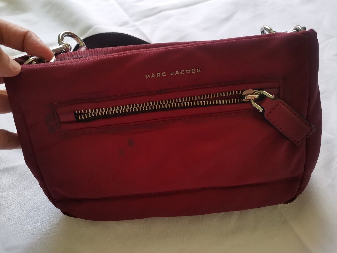 Marc Jacobs red nylon crossbody bag (Category: Luxury Bags & Wallets) located in Daet. Submitted by prelovedatbp (Listing ID 1470008511, Image 2). Description: - Authentic Marc Jacobs crossbody bag in vibrant red nylon - Elegant gold hardware accents and front zip pocket - Adjustable dark strap with chic leather trim - Sturdy zippers and smooth-working metal clasps - Clean overall shape with minor marks near the front zipper.