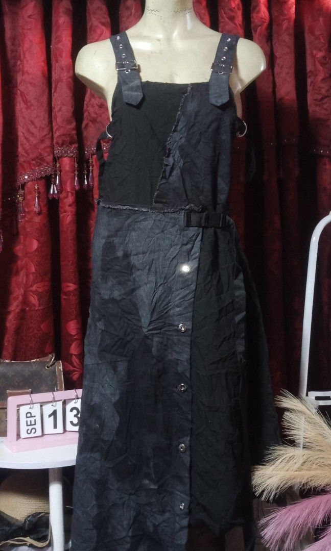 Maxi jumpsuit (Category: Jumpsuits) located in Manila. Submitted by wheneity67thifted (Listing ID 1470136446, Image 1). Description: The image shows a black denim or cotton overall-style maxi dress featuring an asymmetrical wrap-and-button front, distressed raw seams, and buckle shoulder straps..