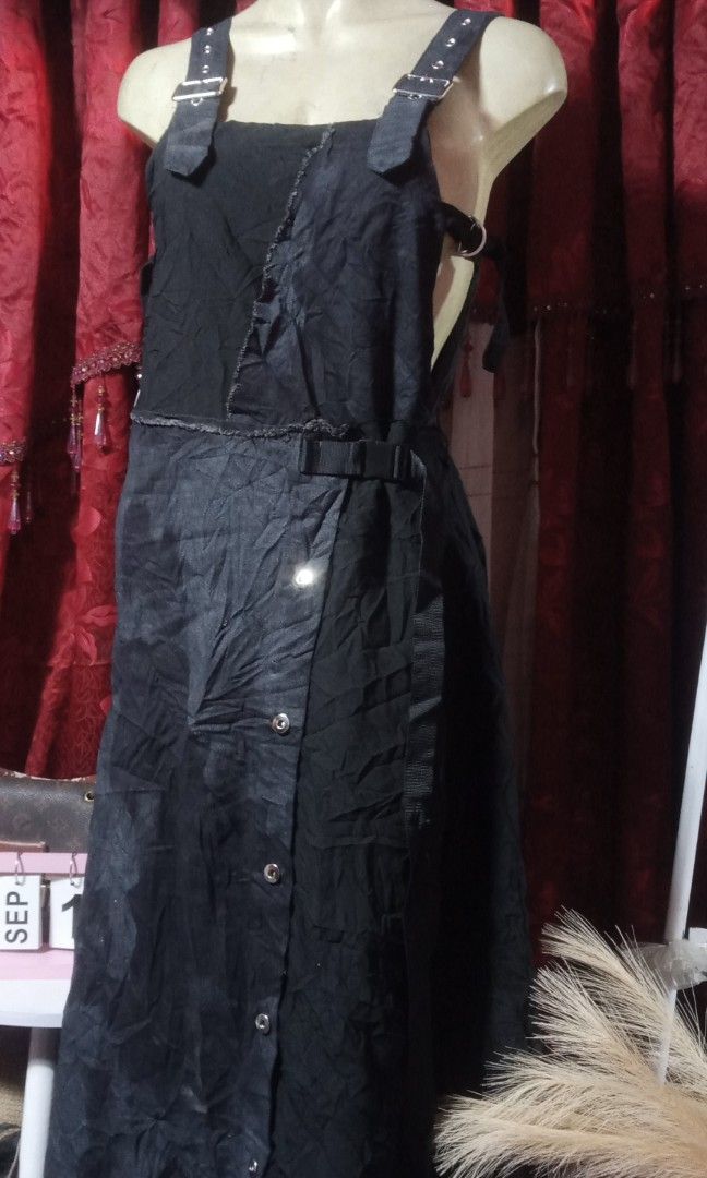 Maxi jumpsuit (Category: Jumpsuits) located in Manila. Submitted by wheneity67thifted (Listing ID 1470136446, Image 2). Description: The image shows a black denim or cotton overall-style maxi dress featuring an asymmetrical wrap-and-button front, distressed raw seams, and buckle shoulder straps..